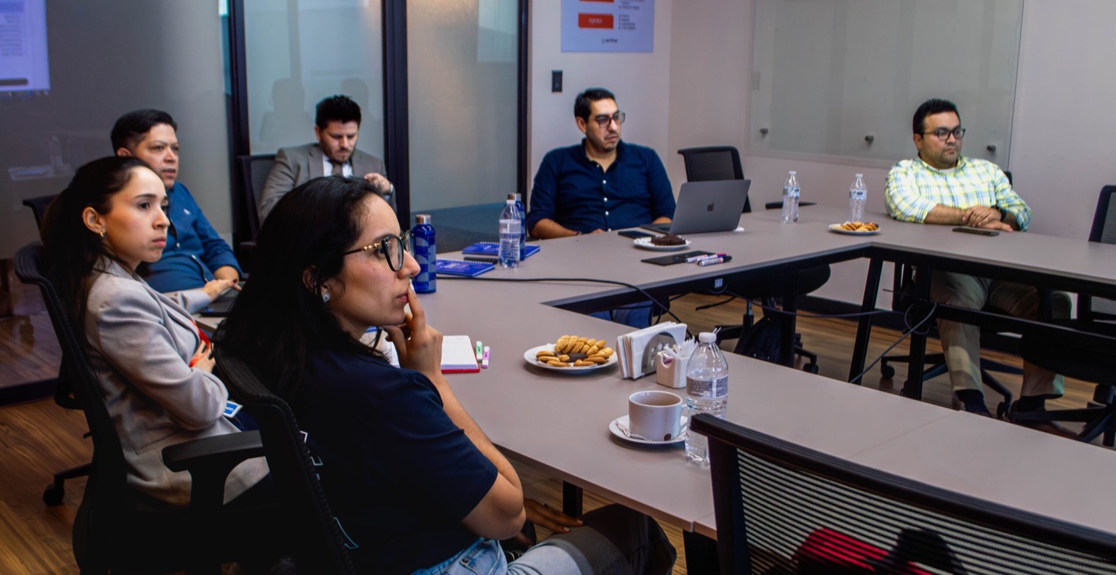 Equipo reunido en una sala de juntas siguiendo la presentación de la alianza