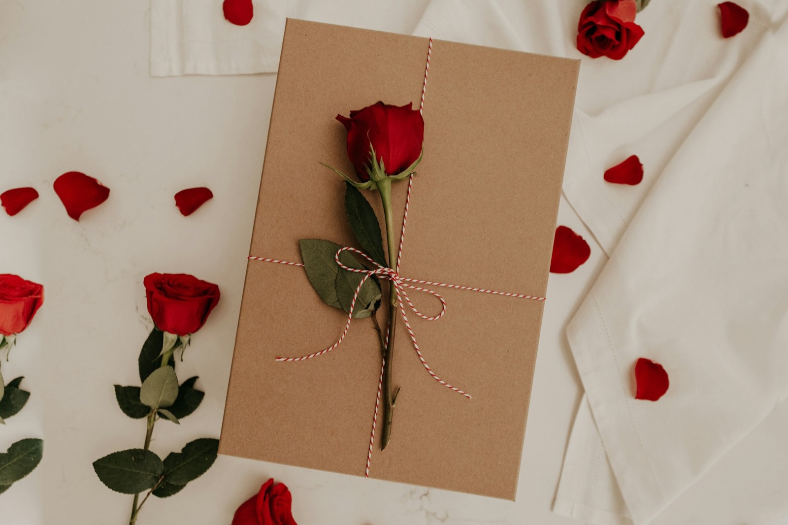 Tarjeta de regalo junto a rosas y pétalos sobre una mesa